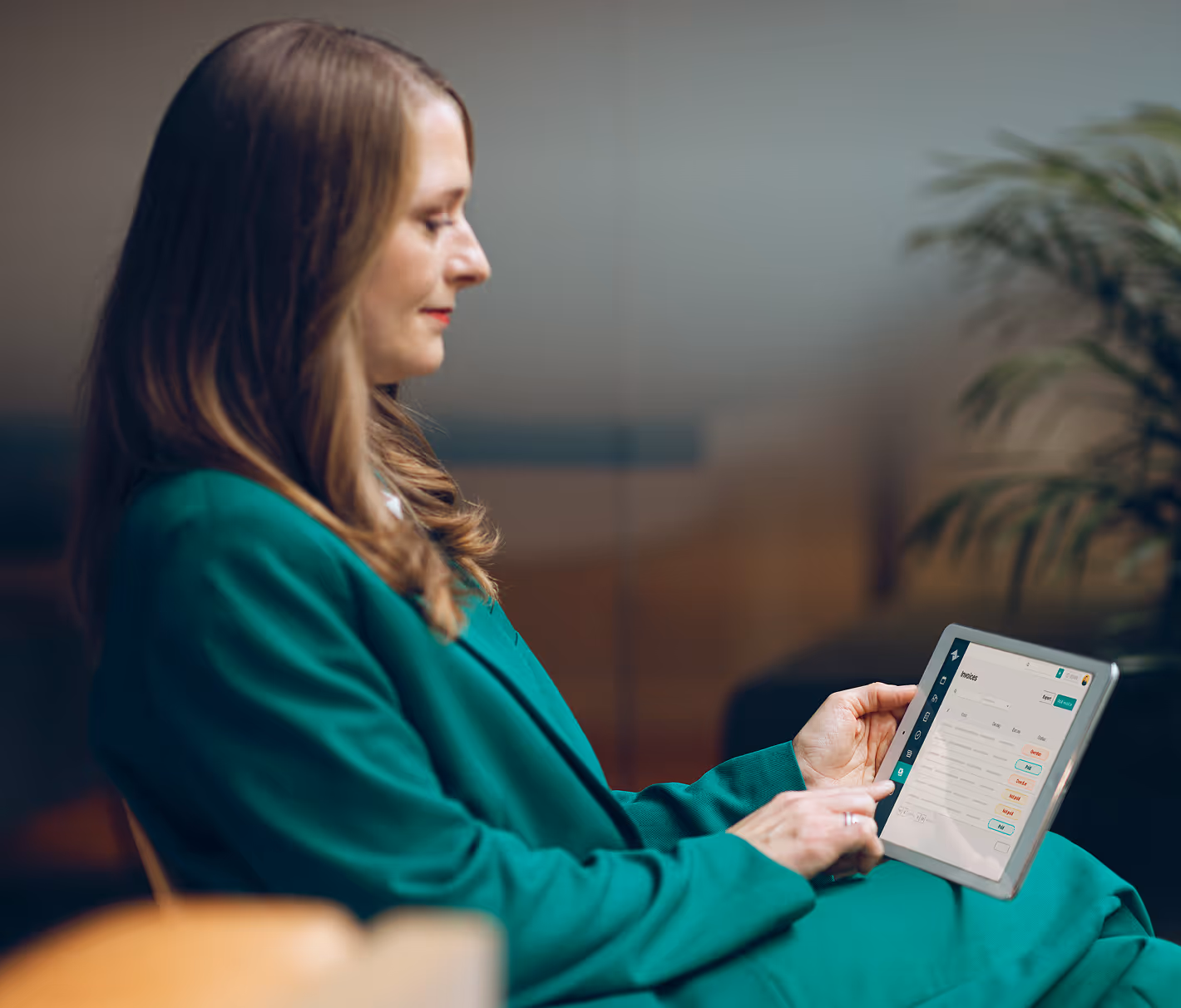 Frau sitzt mit Tablet in der Hand