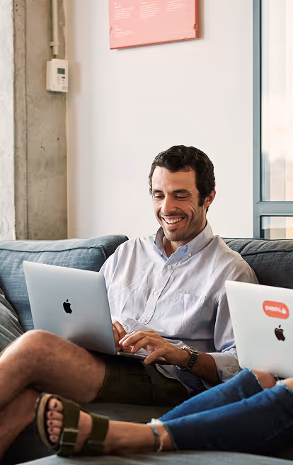 Mann mit Laptop im Schoß auf der Couch