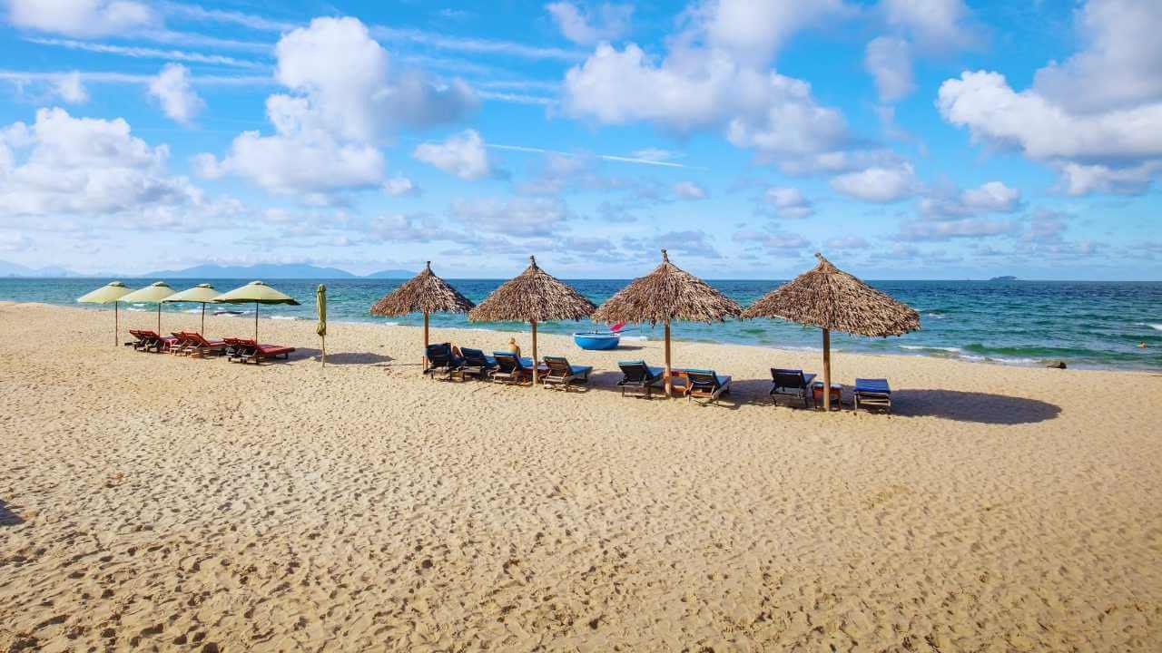 Thatched umbrellas and sun loungers on the sands of An Bang Beach, Hoi An.