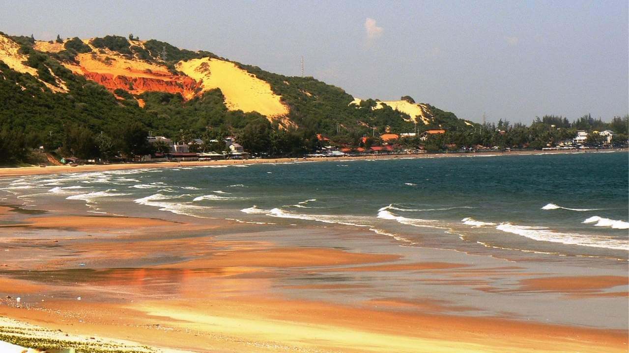 The iconic red sand dunes meeting the sea at Mui Ne Beach.