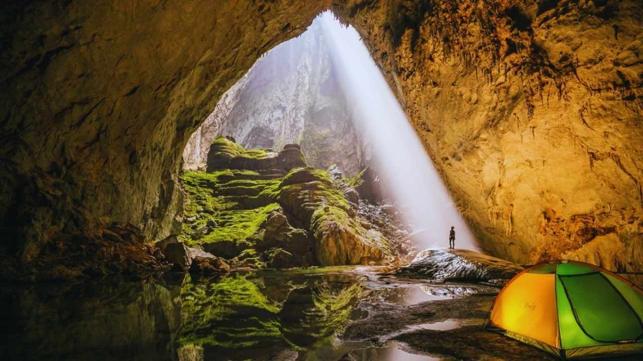 An explorer stands under a sunbeam during a Son Doong Cave expedition in Quang Binh.