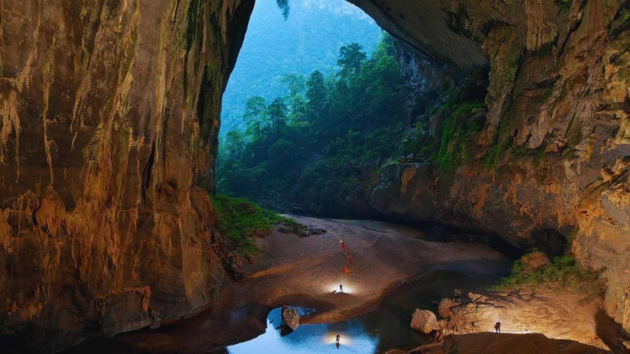 The massive jungle entrance of Hang En Cave seen from the inside during a trekking tour.