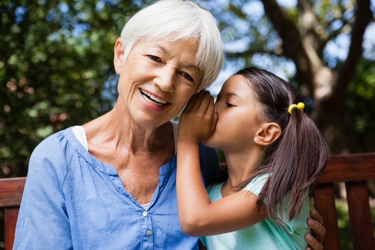 A photo of a little girl whispering something on the old lady
