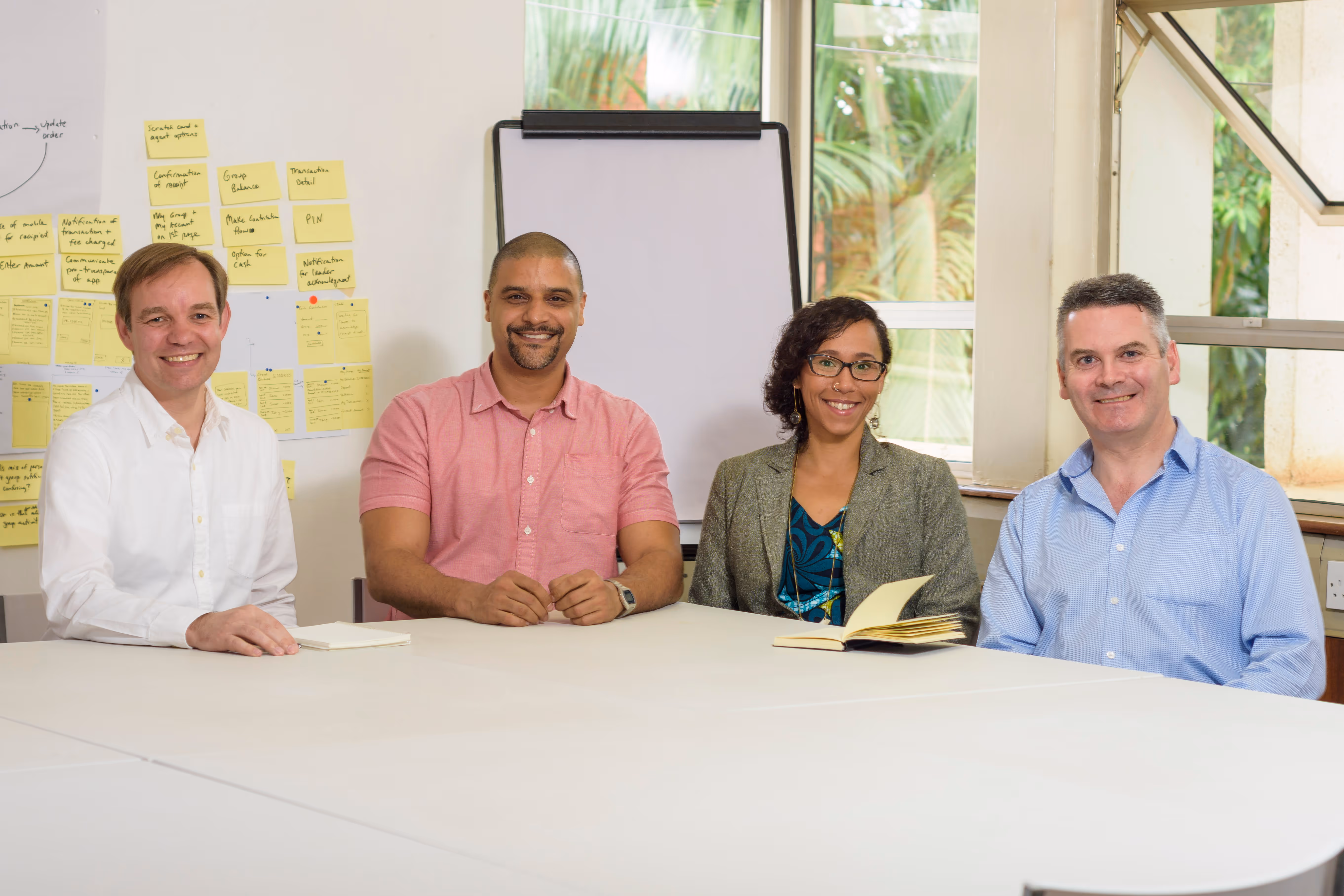 Foxfire's Founder, Dacia, is sitting at a boardroom table with a few of her colleagues. They're all posing for the photo and smiling.