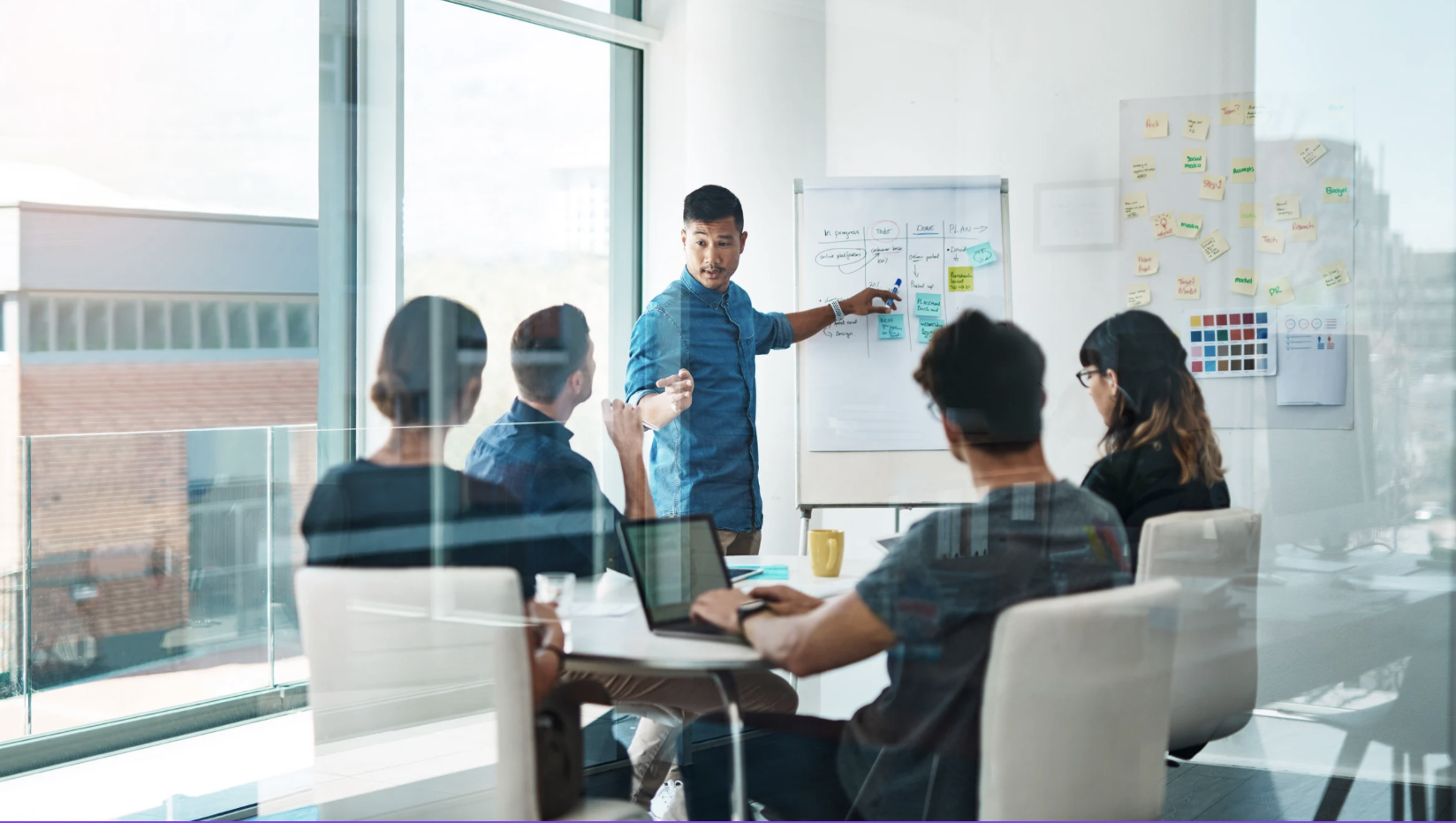 A close-up of a person working on a laptop. The laptop is displaying charts and statistics.