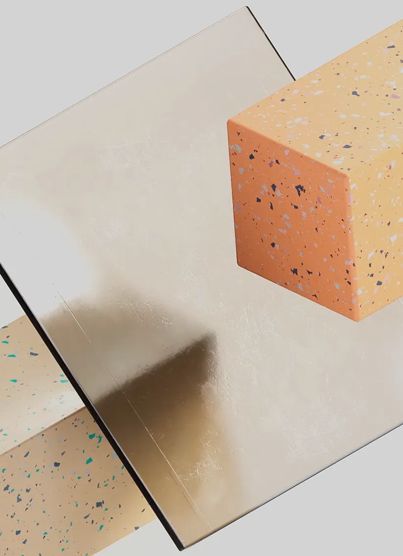 Dos cubos con diseño de terrazzo en colores naranja y beige, con un espejo cuadrado entre ellos sobre fondo gris.