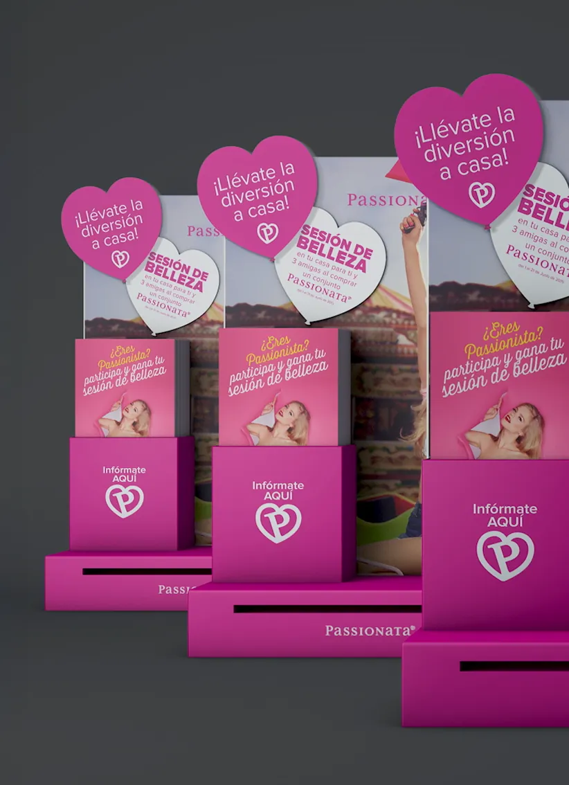 Expositores rosas con folletos y globos en forma de corazón que promocionan una sesión de belleza de Passionata con el texto '¡Llévate la diversión a casa!'