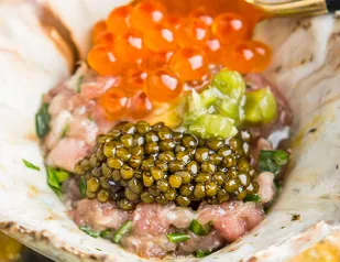 Caviar negro y huevas de salmón sobre una base de pescado crudo y aguacate.