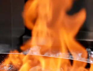 Llama intensa y brillante sobre parrilla metálica en cocción.