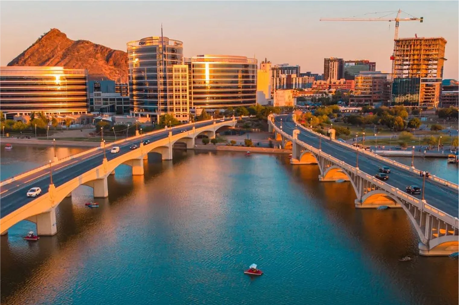Aerial view of a river with bridges and buildings during sunset in Tempe.