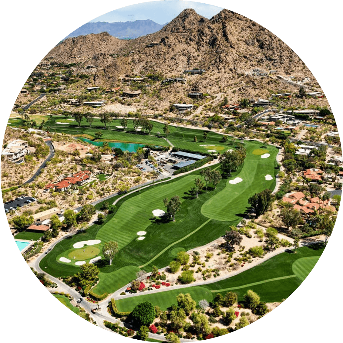 Aerial view of a golf course surrounded by desert mountains and houses.