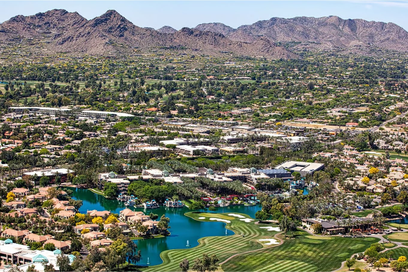 Scenic aerial view of a desert community with a lake and surrounding mountains.