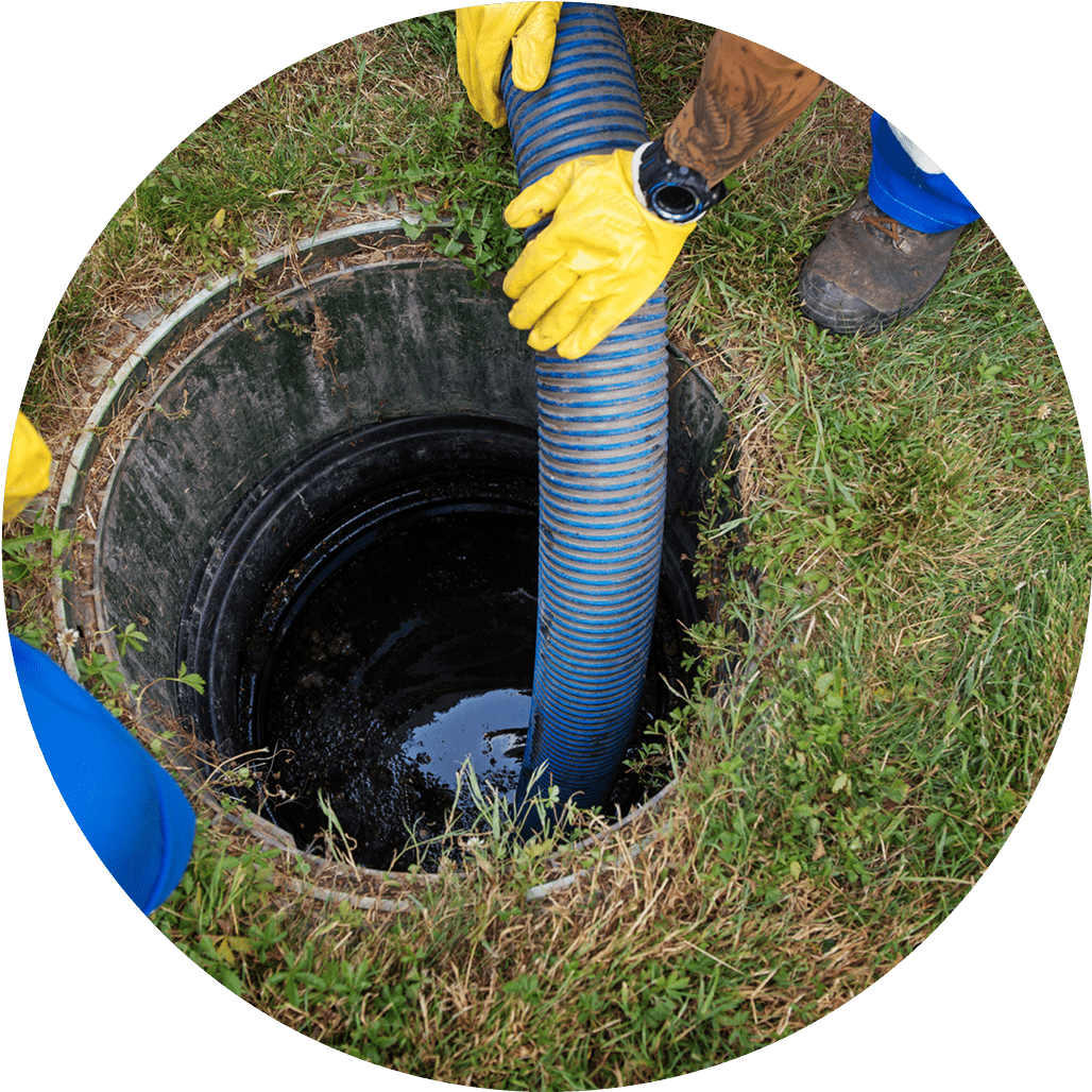 Worker in yellow gloves lowering a hose into a drain opening.