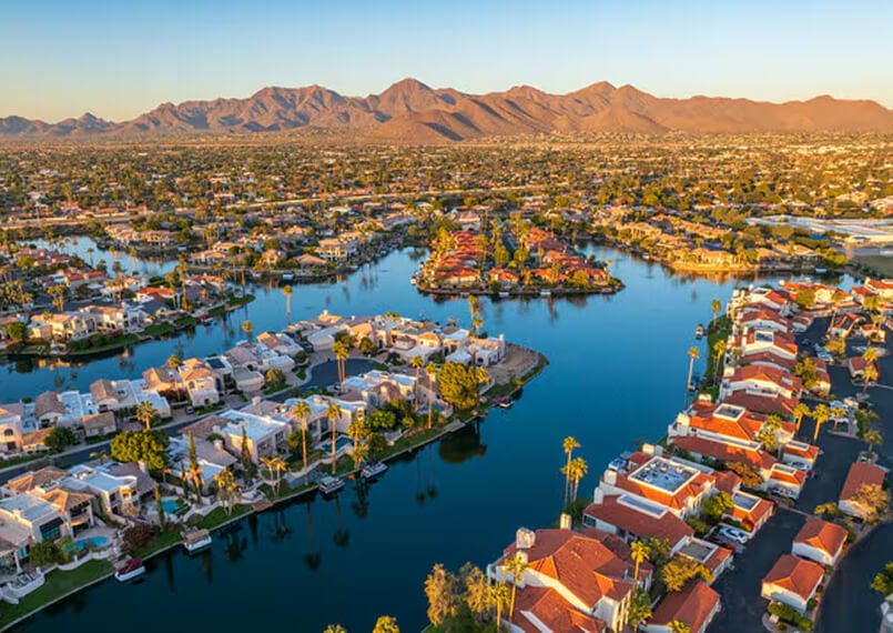 Aerial view of Scottsdale with a lake, homes, and desert mountains.