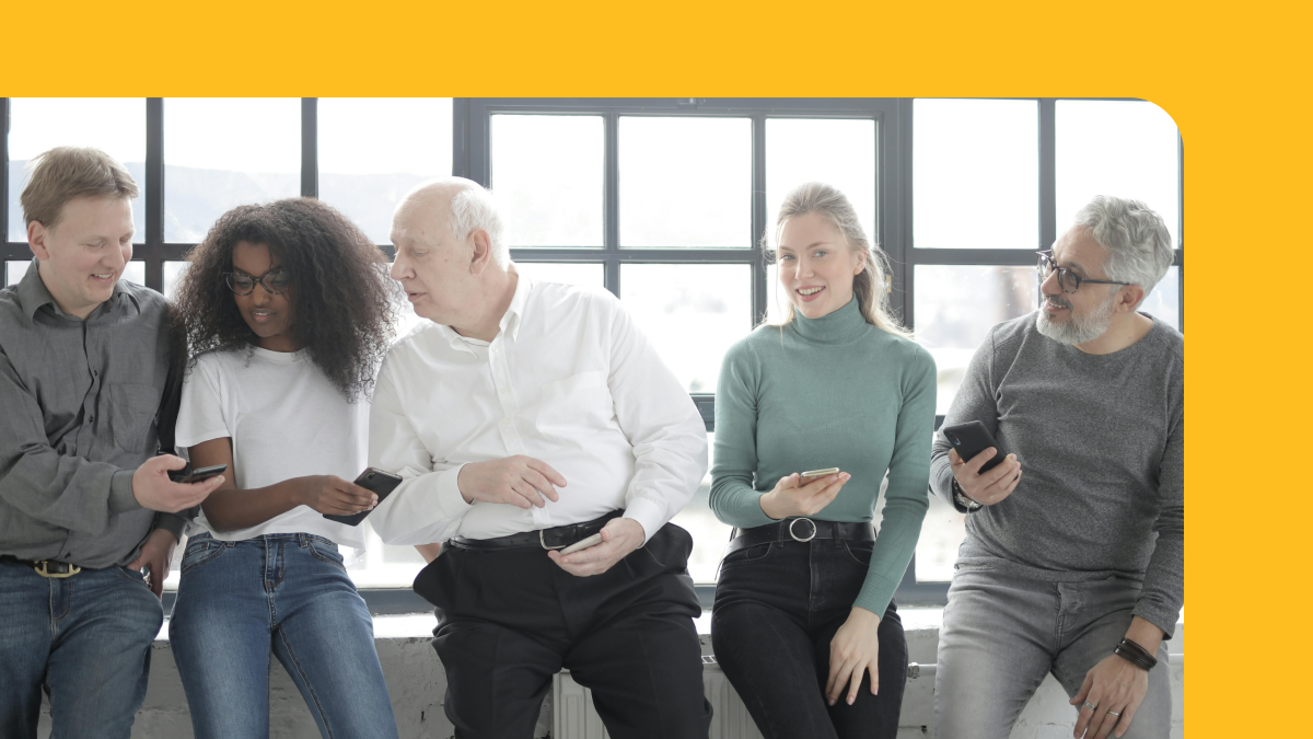 diverse group of people checking their phones by a window