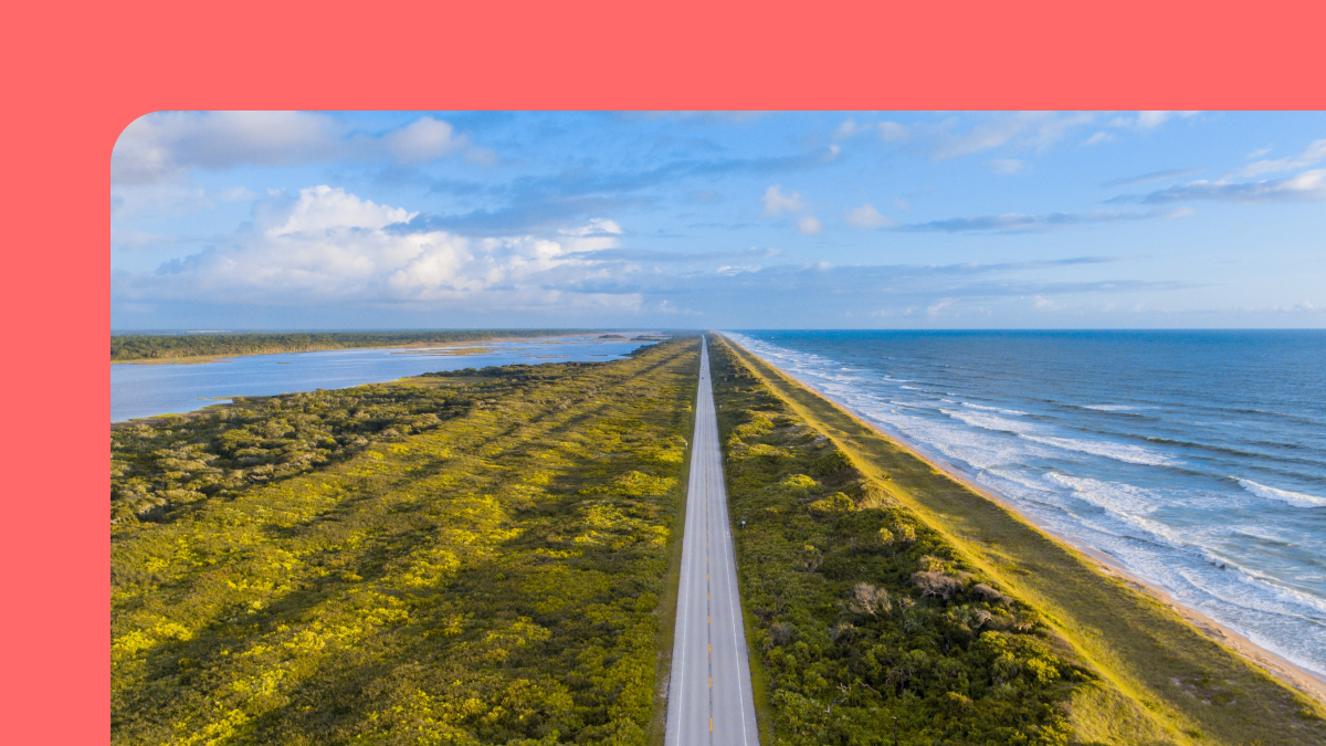 Image of road on land next to waves by the sea