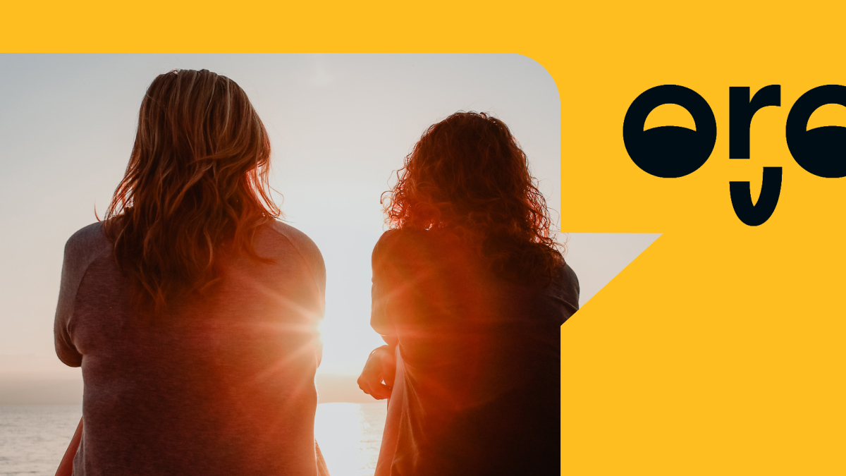 Two women look out at a sunset on the beach