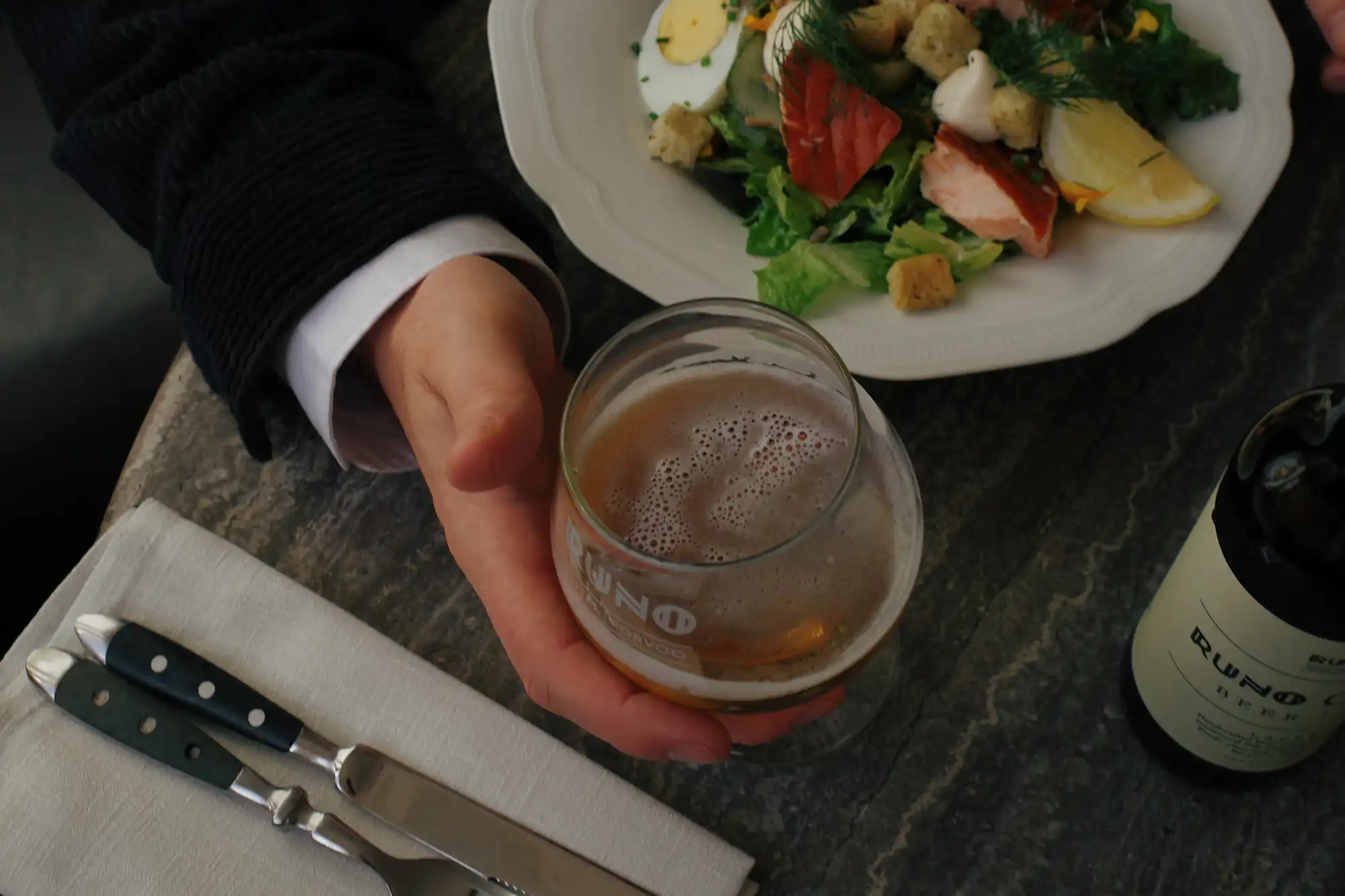 Kauniisti katettu ateria ja olutlasi kädessa