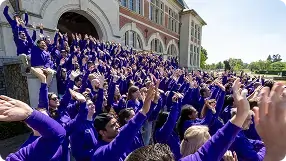 Side view of the GoodHabitz team gathered on the steps of an old building with their hands in the air