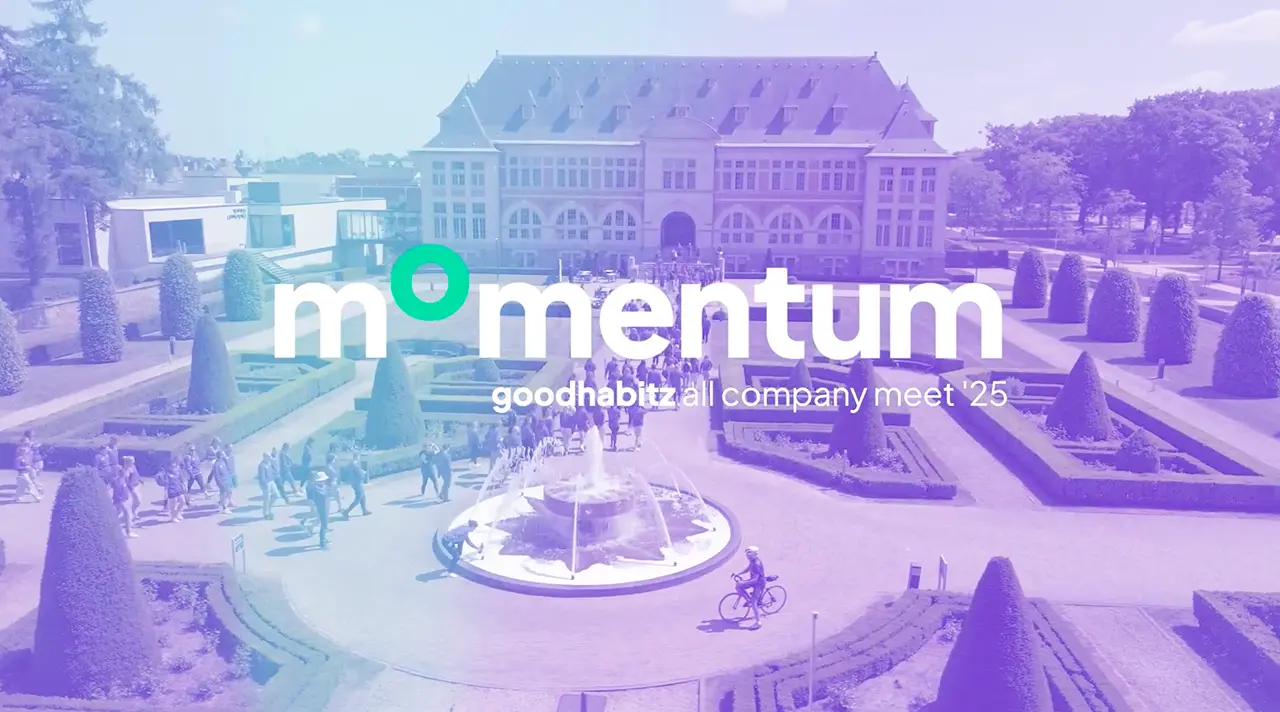 A large historic building and landscaped garden with shaped bushes and a central fountain, overlaid with the text 'momentum goodhabitz all company meet '25'.