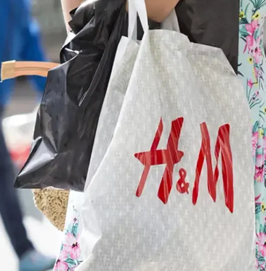A person carrying an H&M shopping bag over their shoulder.