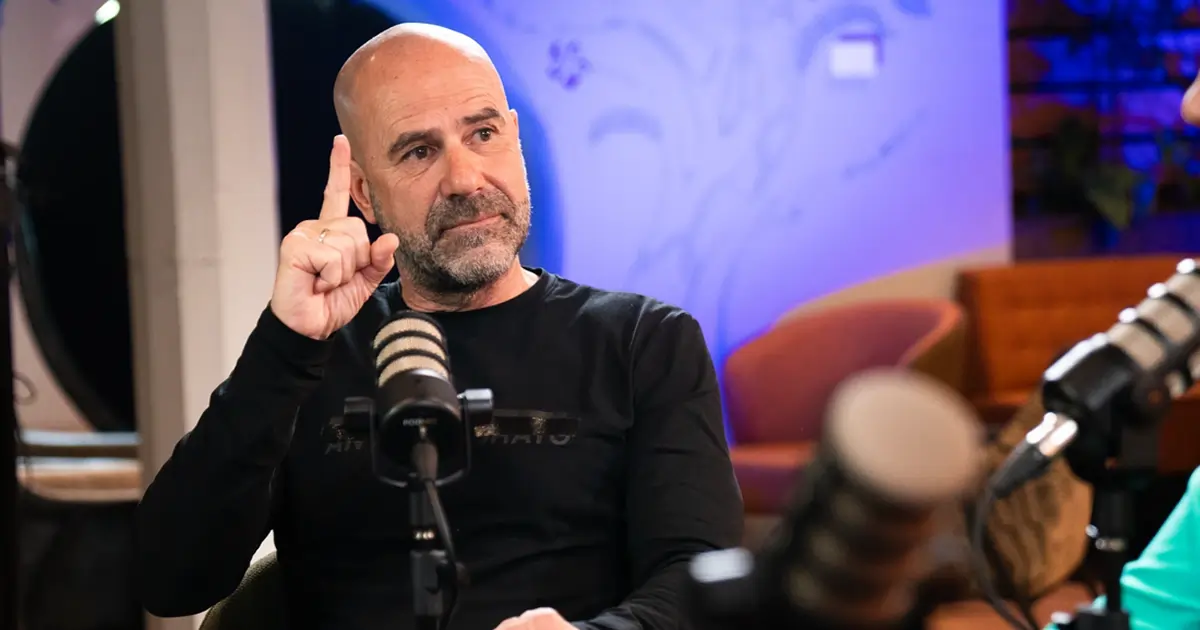 Peter Bosz in front of a podcast mic holding one finger in the air