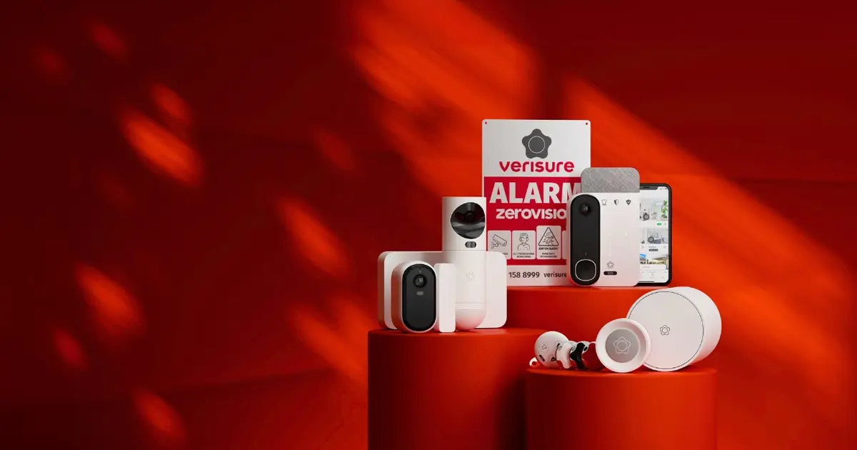 Une collection de dispositifs de sécurité Verisure sur un fond rouge. On y voit plusieurs caméras, un panneau d'alarme, un smartphone affichant une application, et d'autres équipements de sécurité.