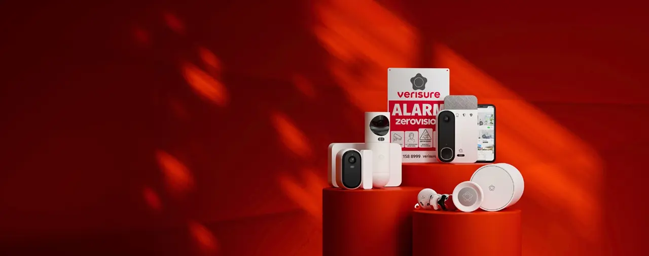 Une collection de dispositifs de sécurité Verisure sur un fond rouge. On y voit plusieurs caméras, un panneau d'alarme, un smartphone affichant une application, et d'autres équipements de sécurité.
