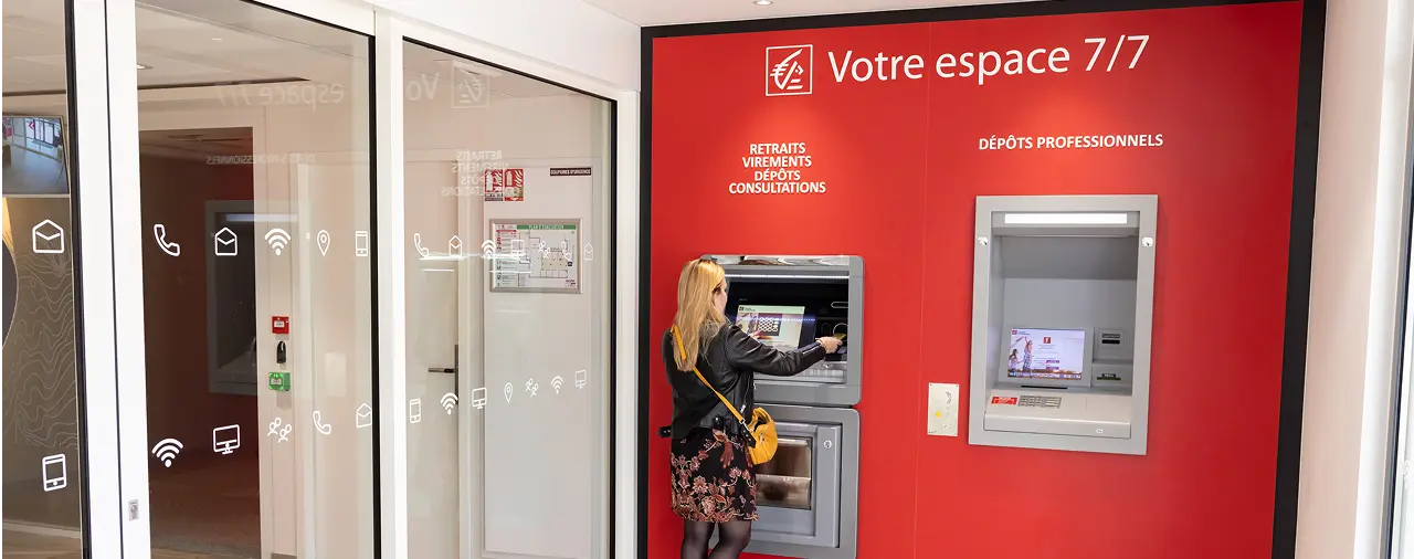 Une femme utilise un distributeur automatique de billets dans un espace bancaire moderne.
