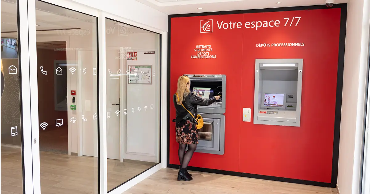 Une femme utilise un distributeur automatique de billets dans un espace bancaire moderne. 