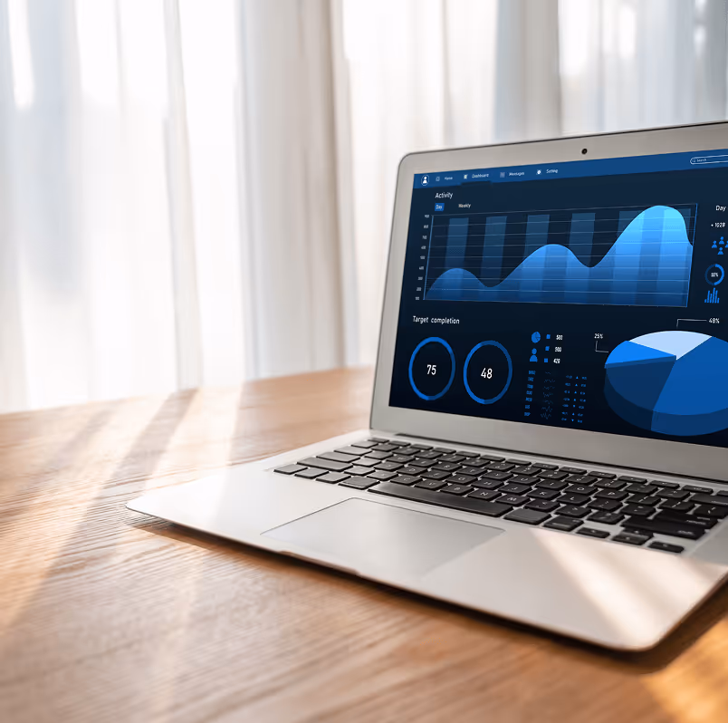 Laptop auf Holztisch, Display zeigt blaue Datenanalysen mit Diagrammen und Statistiken, sanftes Tageslicht im Hintergrund.
