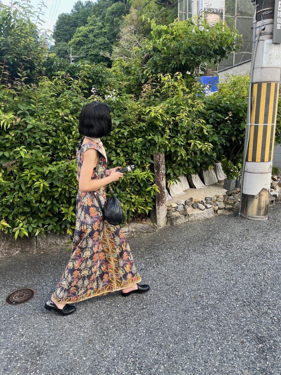 A photograph of a recent sound walk guest who joined a Kyoto, in Sound walk. This is a photograph of a young lady walking through the streets of Kyoto holding a sound recorder.