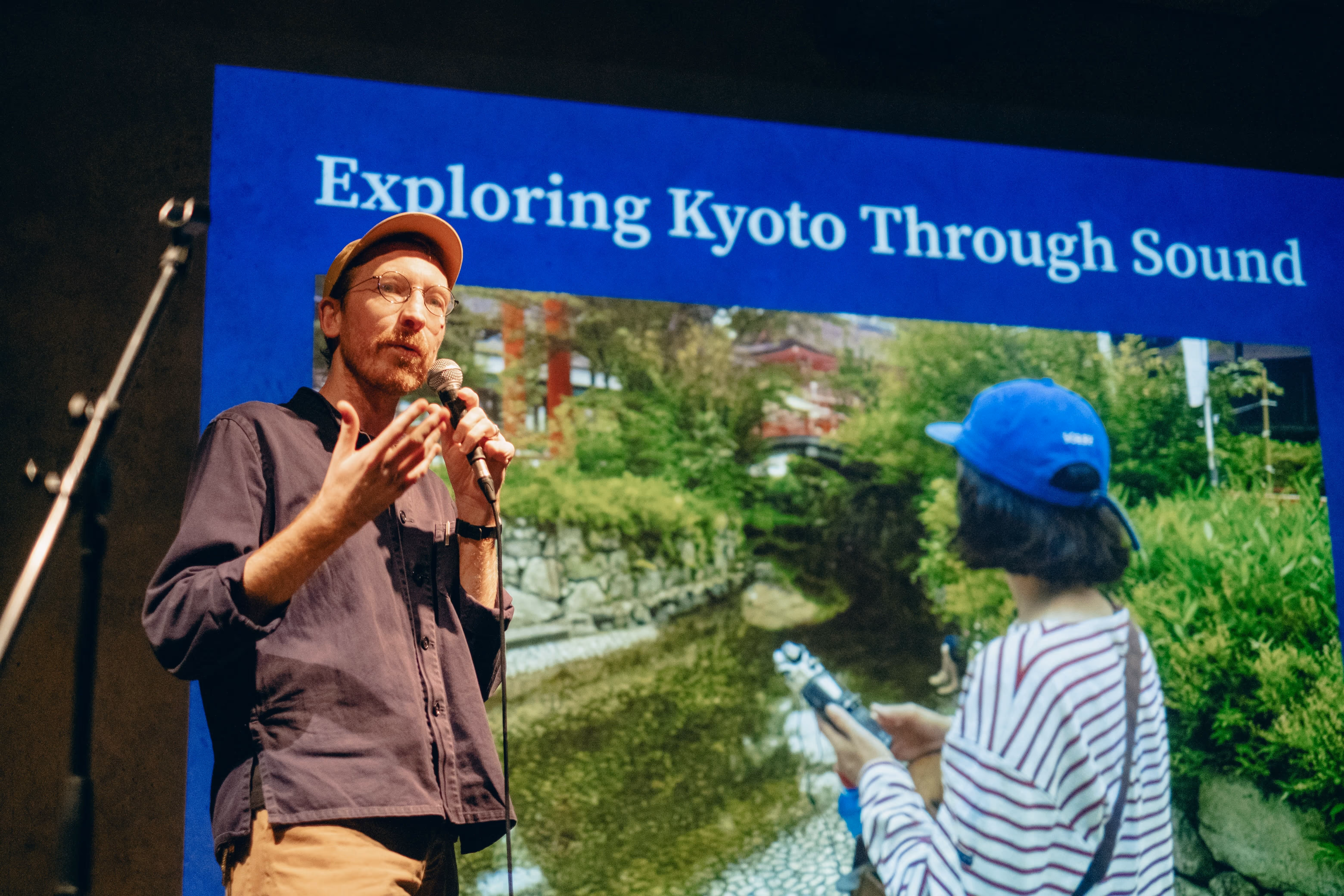 Simon giving a presentation at Pecha Kucha Kyoto. He is standing in front of a slide that says "Exploring Kyoto Through Sound".