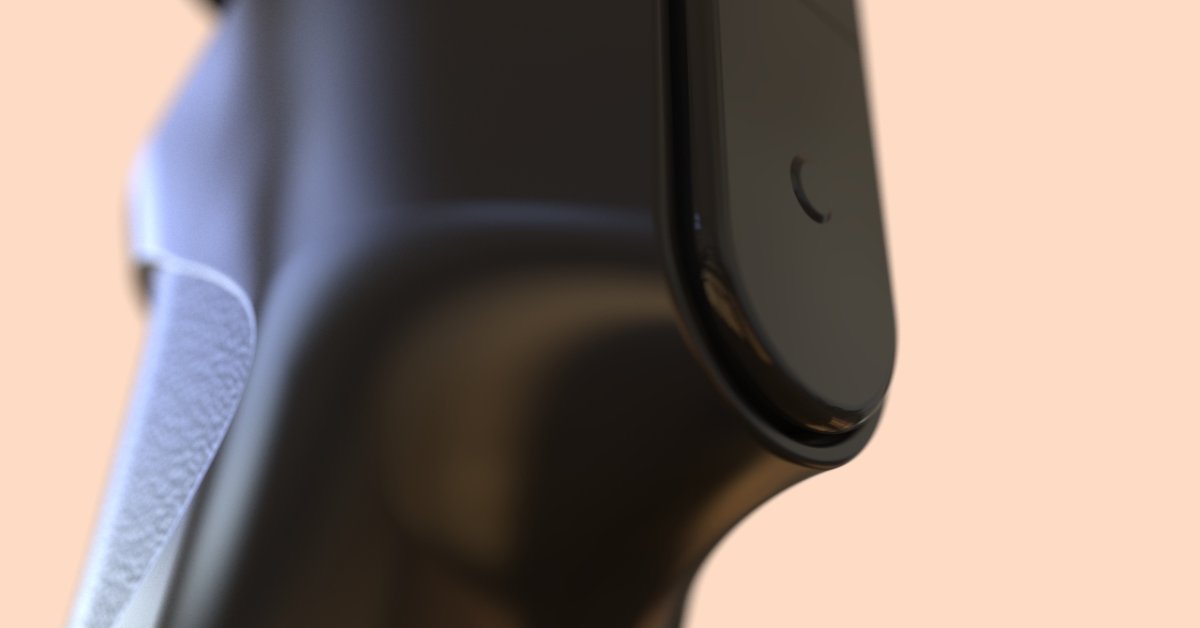 A close-up of a black handheld electronic device with a textured gray grip and curved edge against a peach background.