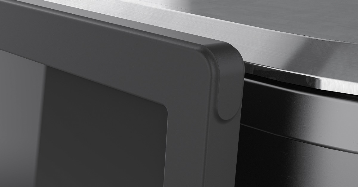 A close-up grayscale view of a dark molded component resting beneath a brushed metal edge and glossy black panel.