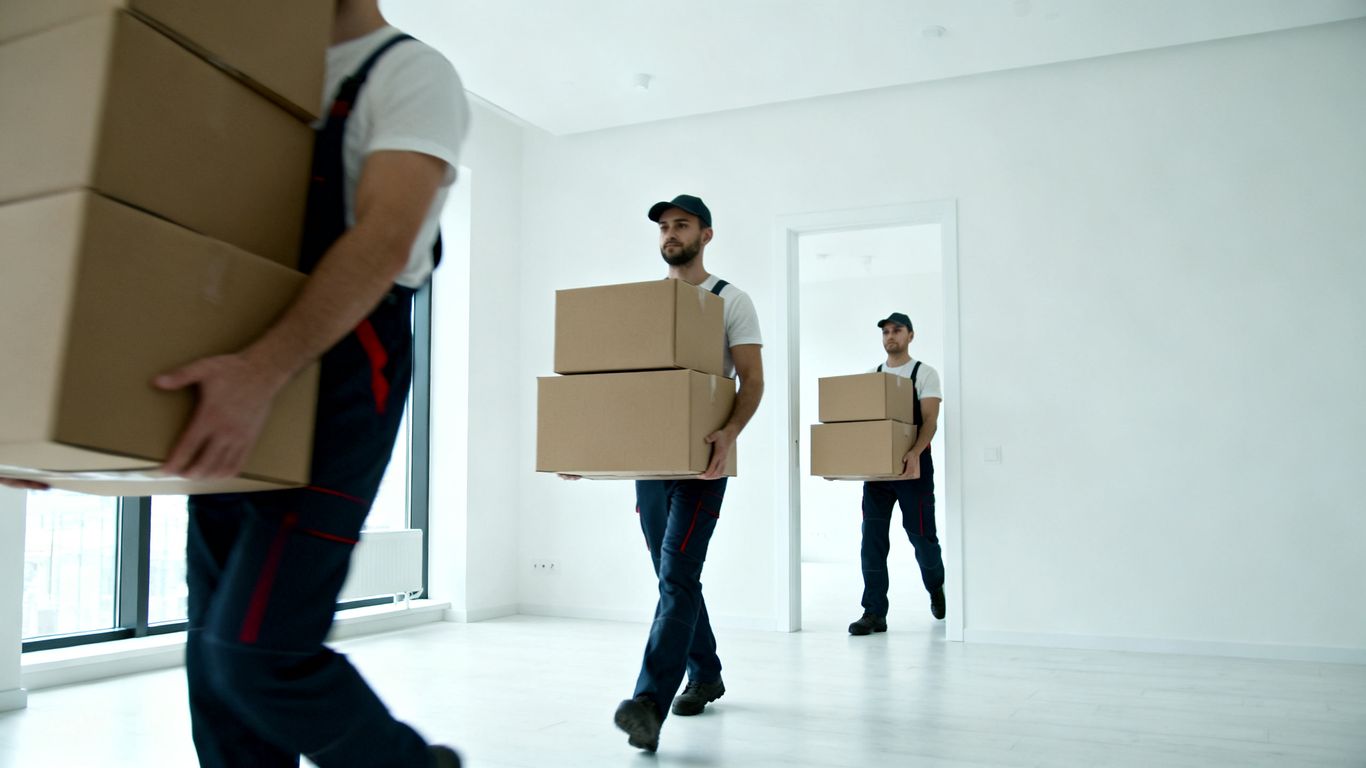 Umzugshelfer tragen Kartons in einer modernen Wohnung.