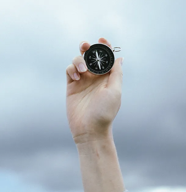 A person holding a compass in their hand.