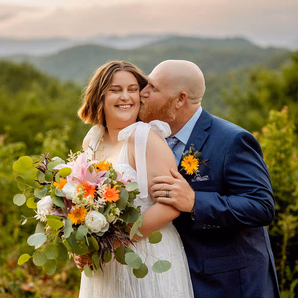 A groom kissing a bride in the Smoky Mountains by Let's Elope Gatlinburg