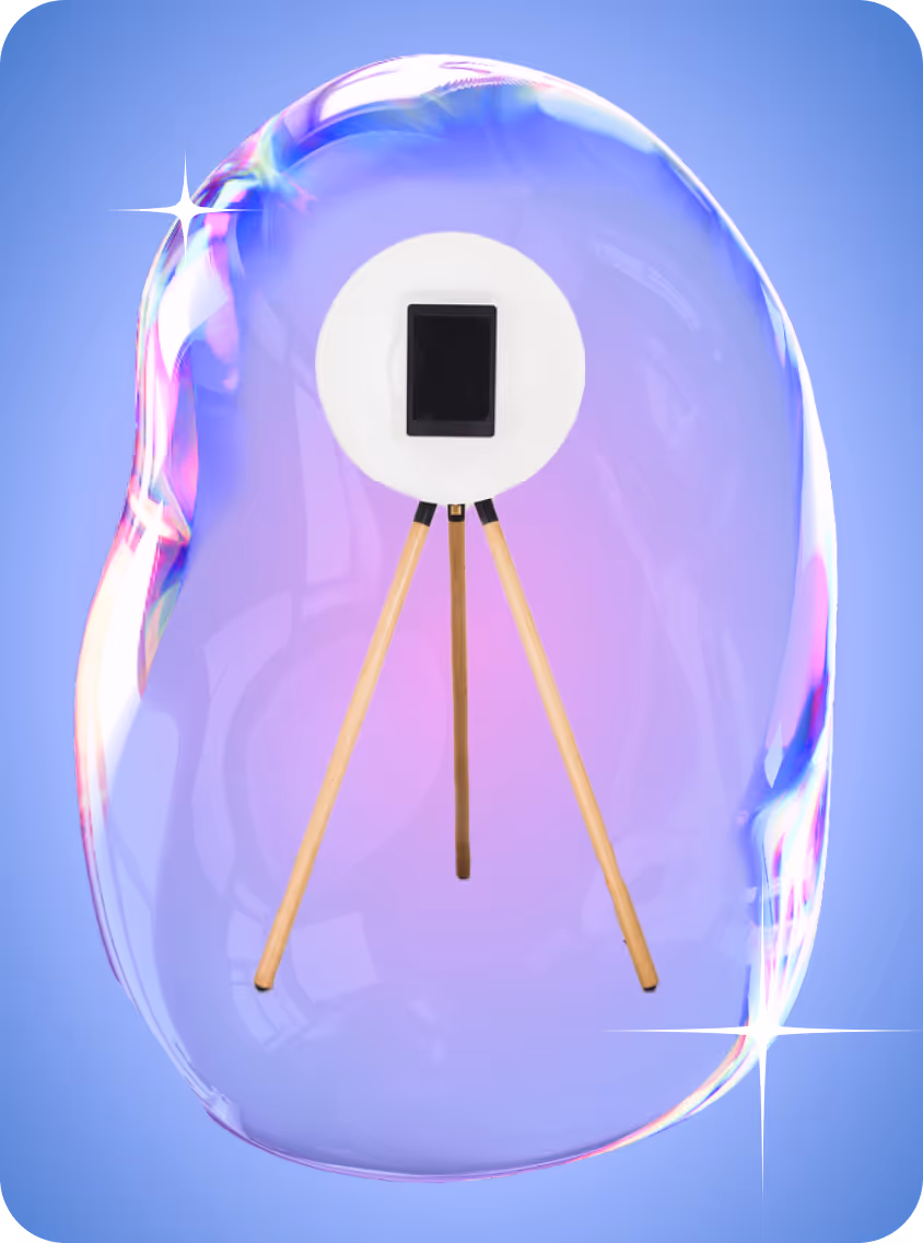 Modern photo booth with a round white ring light mounted on wooden tripod legs inside a translucent, colorful bubble.