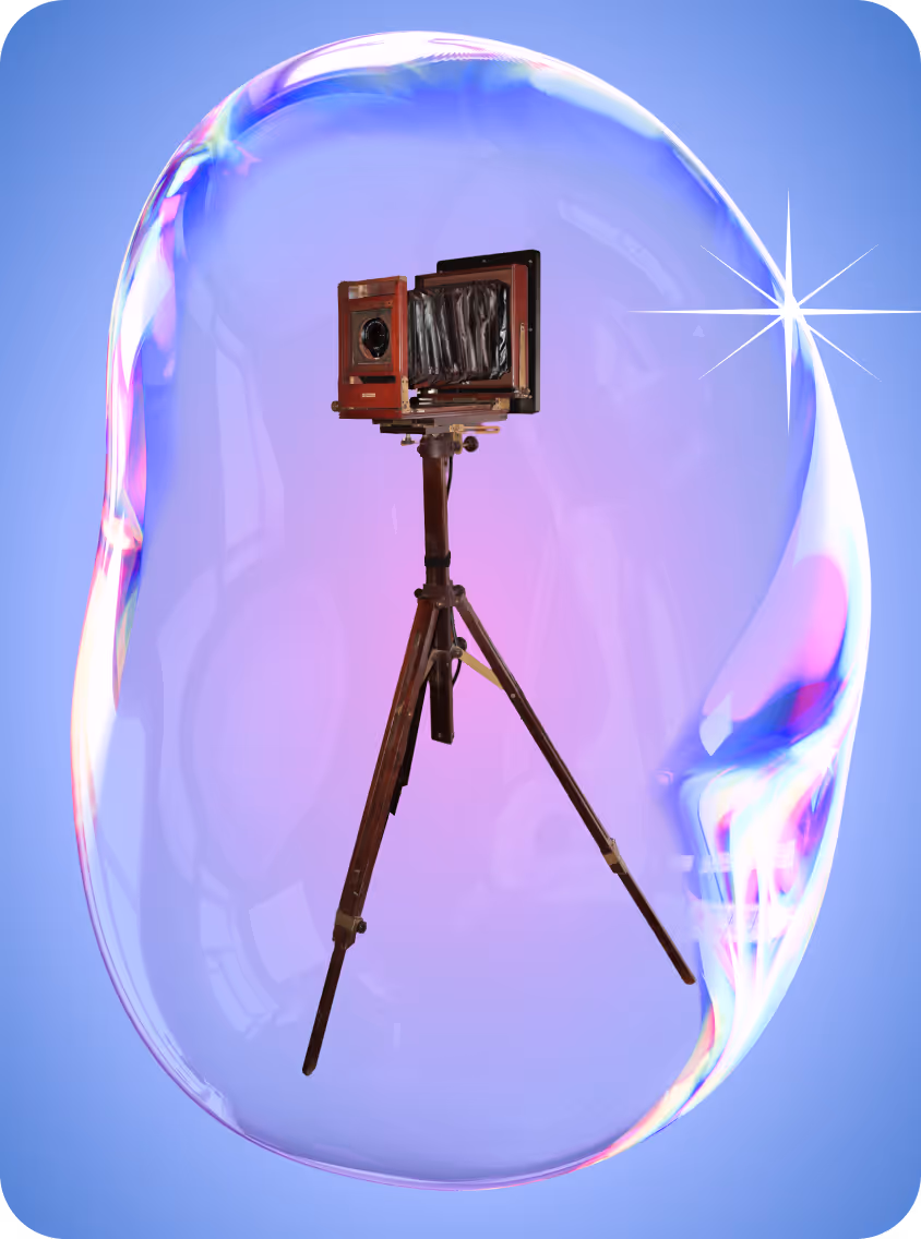 Vintage large format camera on a tripod enclosed inside a translucent soap bubble with rainbow reflections against a blue background.