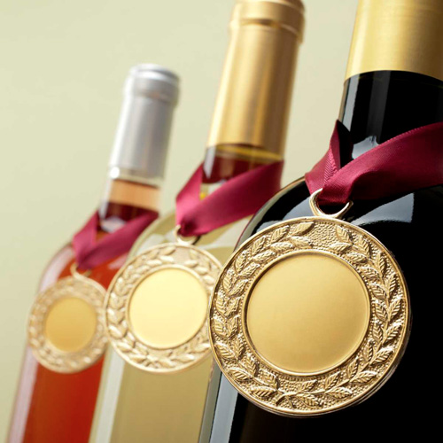 Wine bottles with gold medals hanging around their necks.