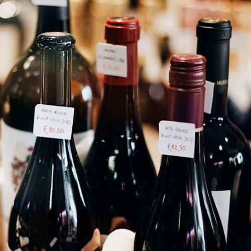 Shelves filled with wine bottles, each with handwritten tags.