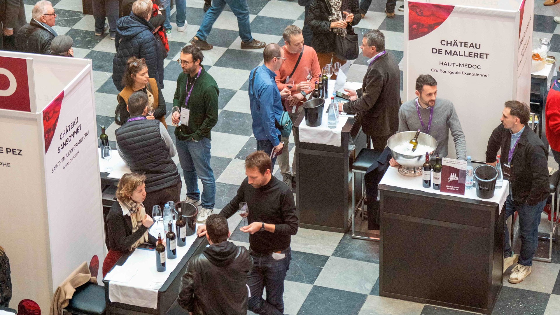 Vue en hauteur de Bordeaux Tasting 2025 montrant des producteurs faisant déguster leurs vins à des visiteurs sur différents stands.