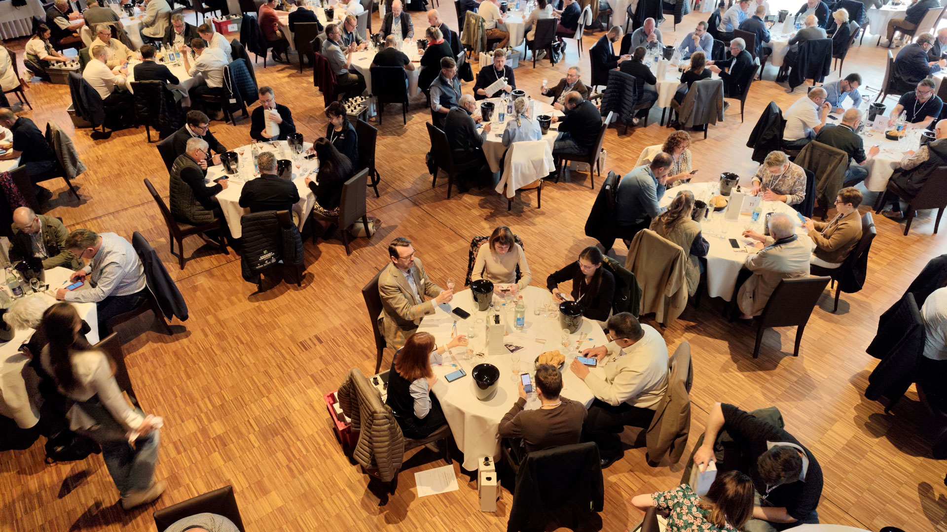 Overhead view of juries at the 2026 Concours National des Crémants tasting and scoring cuvées on smartphones with Tastee