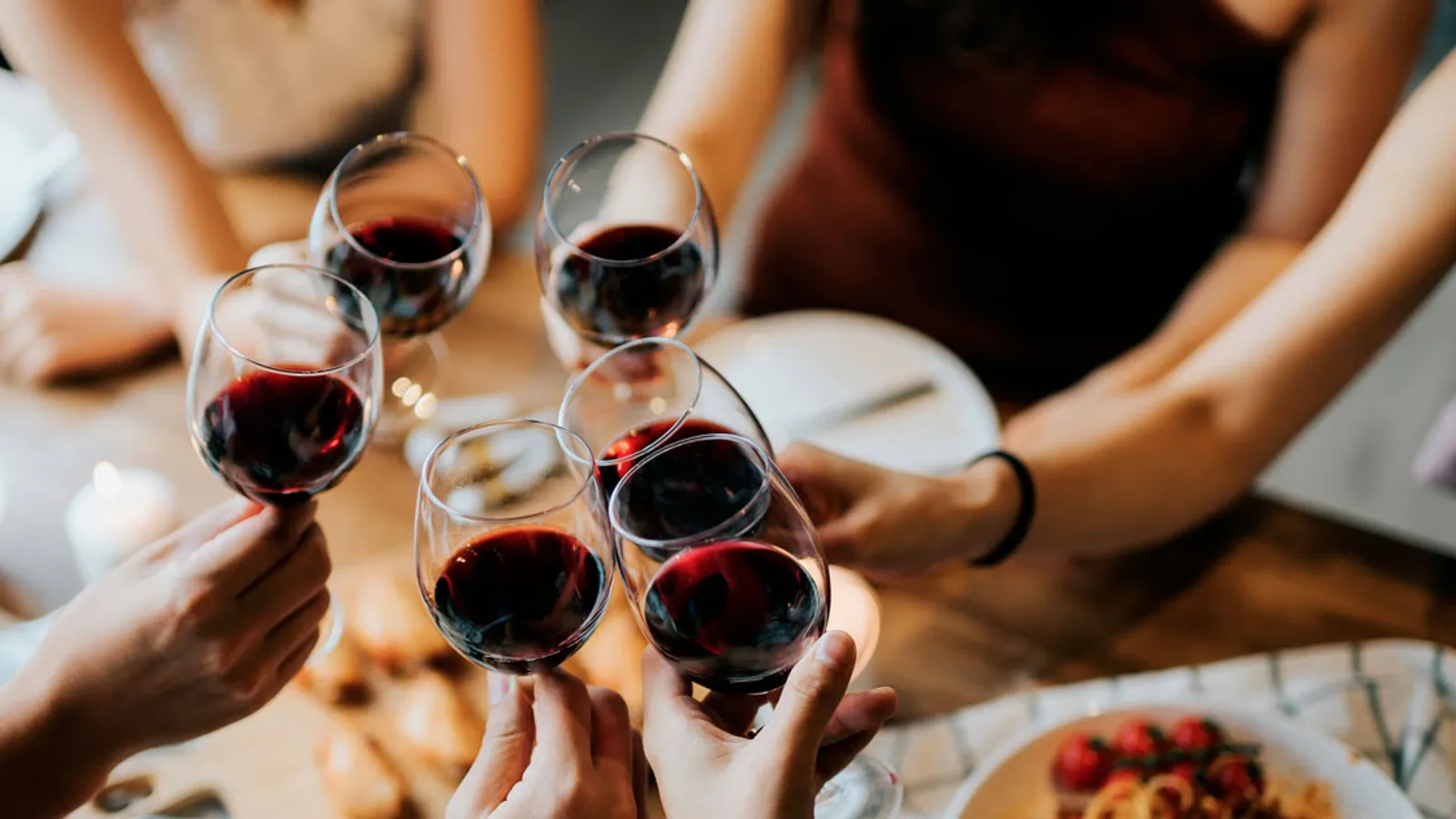 Wine lovers raising glasses of red wine around a table