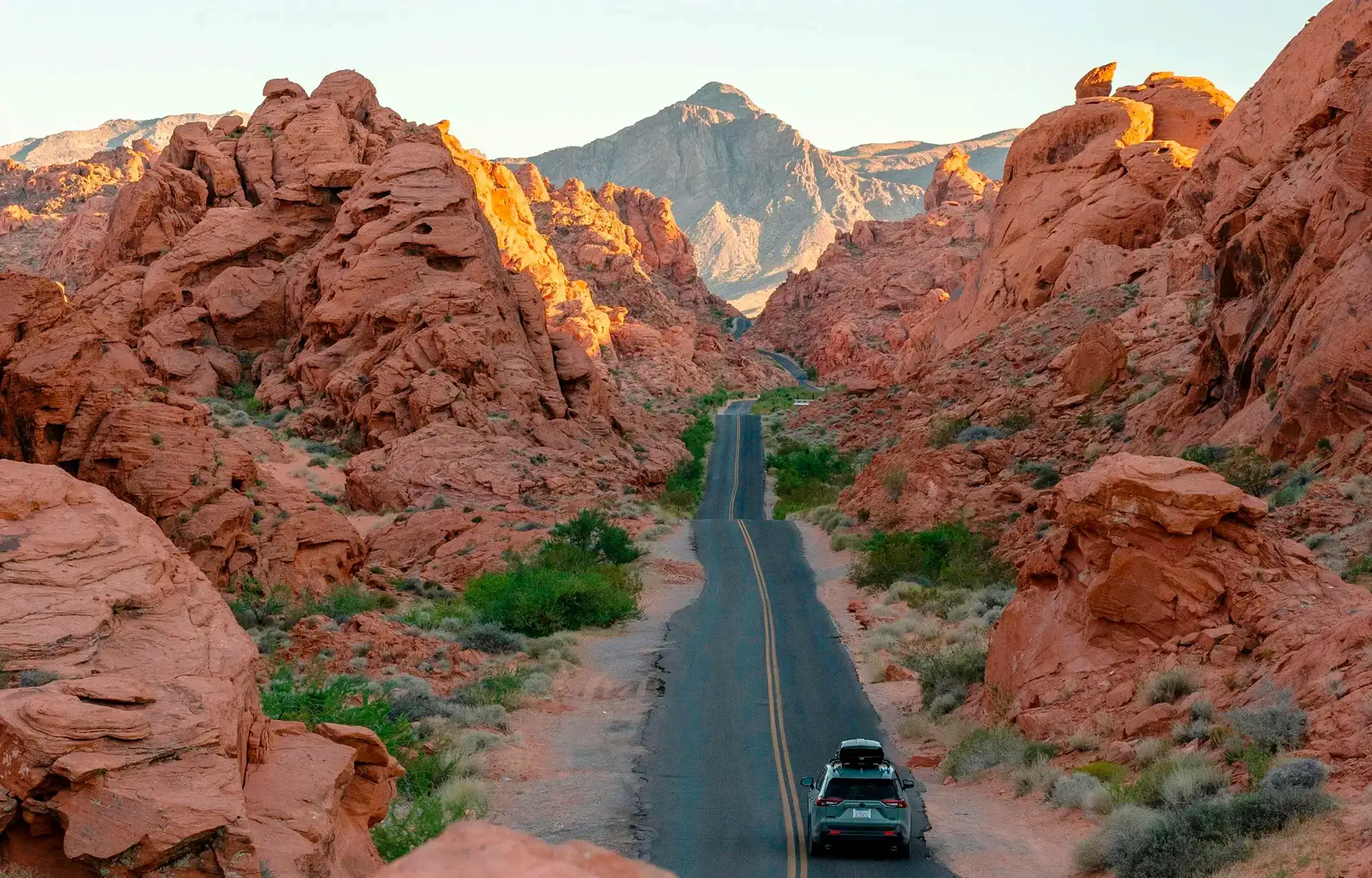 Car driving along a winding desert road through red rock canyons