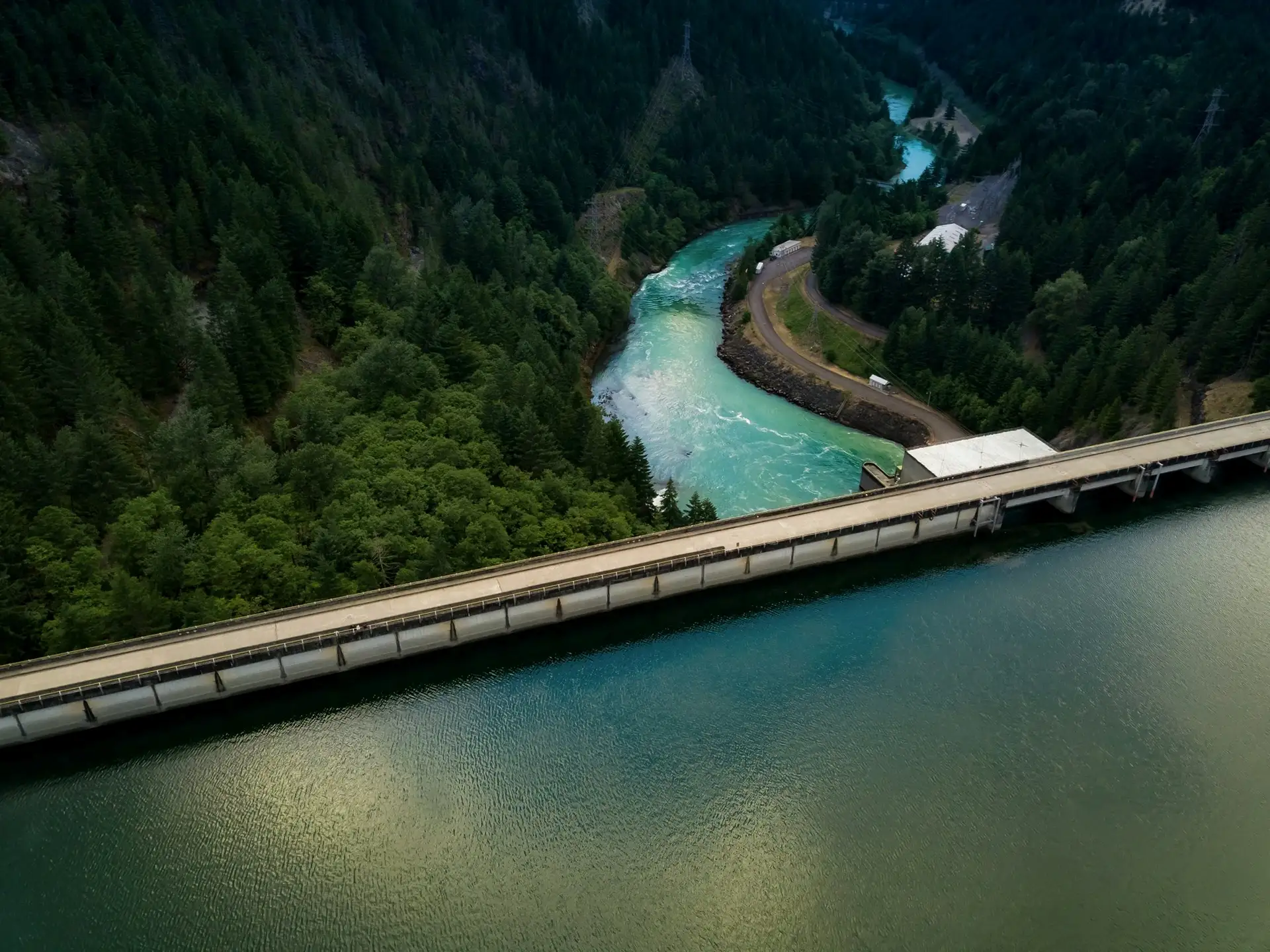 Aerial view of a hydroelectric dam and reservoir surrounded by forest