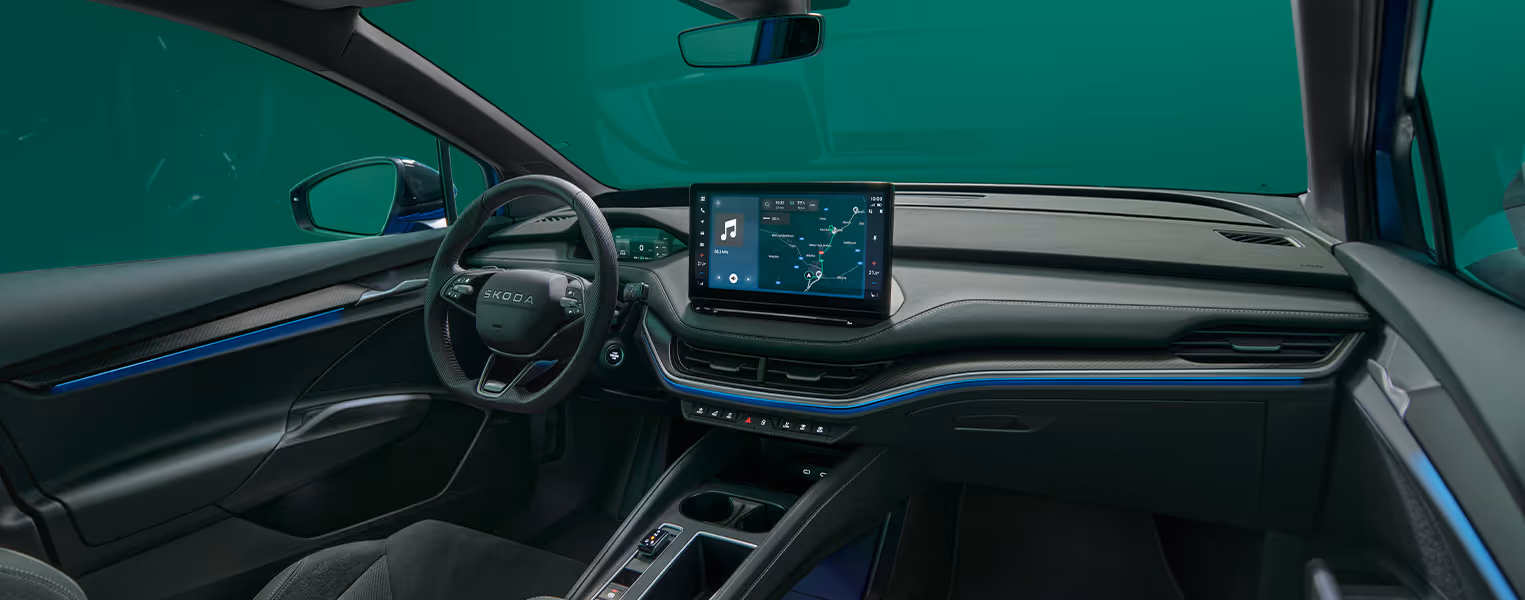 Das Cockpit des Škoda Elroq mit Blick auf das Lenkrad und den freistehenden 13-Zoll-Infotainmentbildschirm. Die blaue Ambientebeleuchtung setzt einen farbigen Akzent entlang des Armaturenbretts und der Türen.