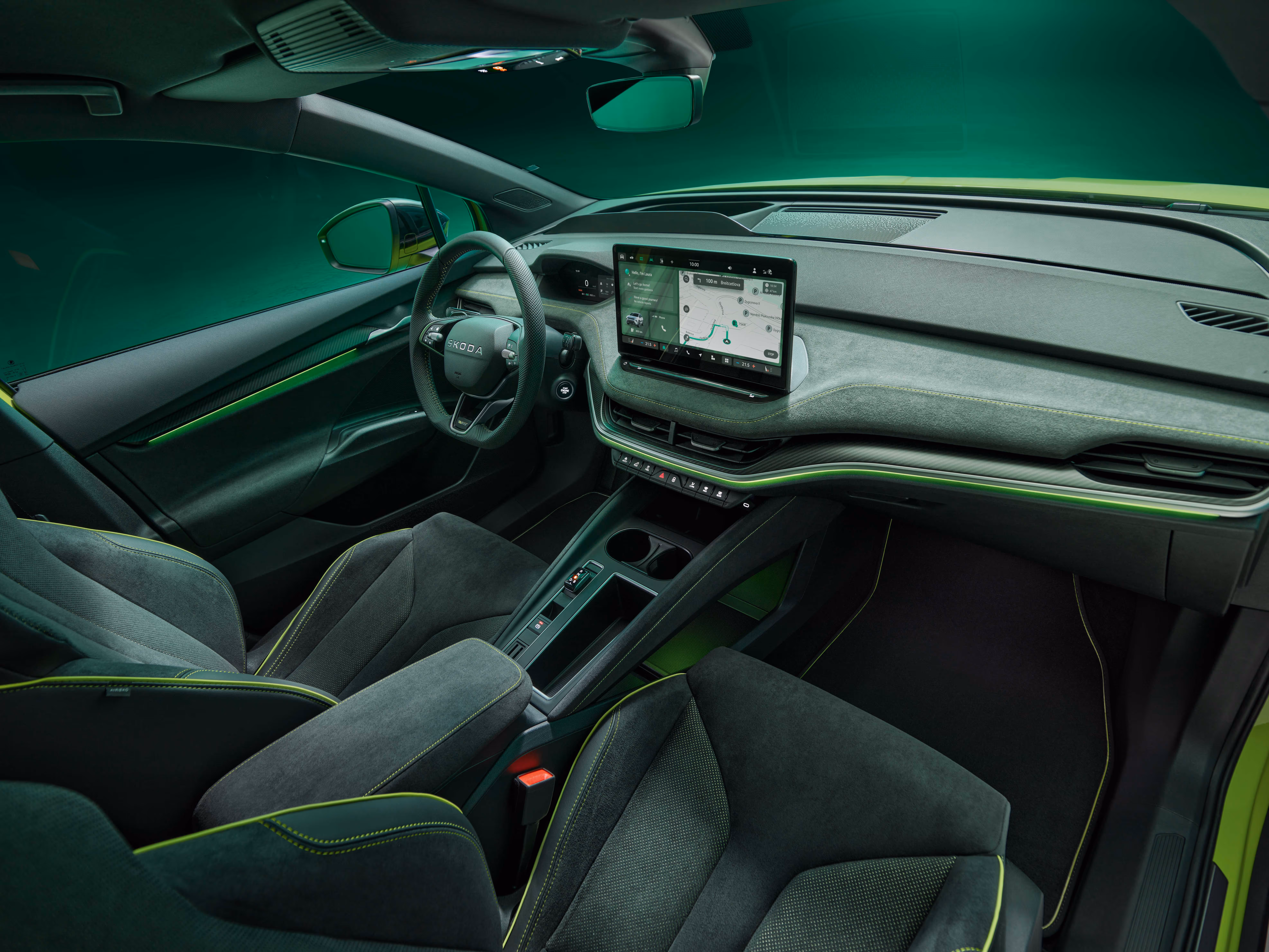 Innenraum des Škoda Elroq RS mit Blick auf das Lenkrad und den freistehenden 13-Zoll-Infotainmentbildschirm. Das Interieur ist mit schwarzem Kunstleder und Suedia Microfaser sowie grünen Ziernähten und Carbon-Dekorleisten gestaltet.