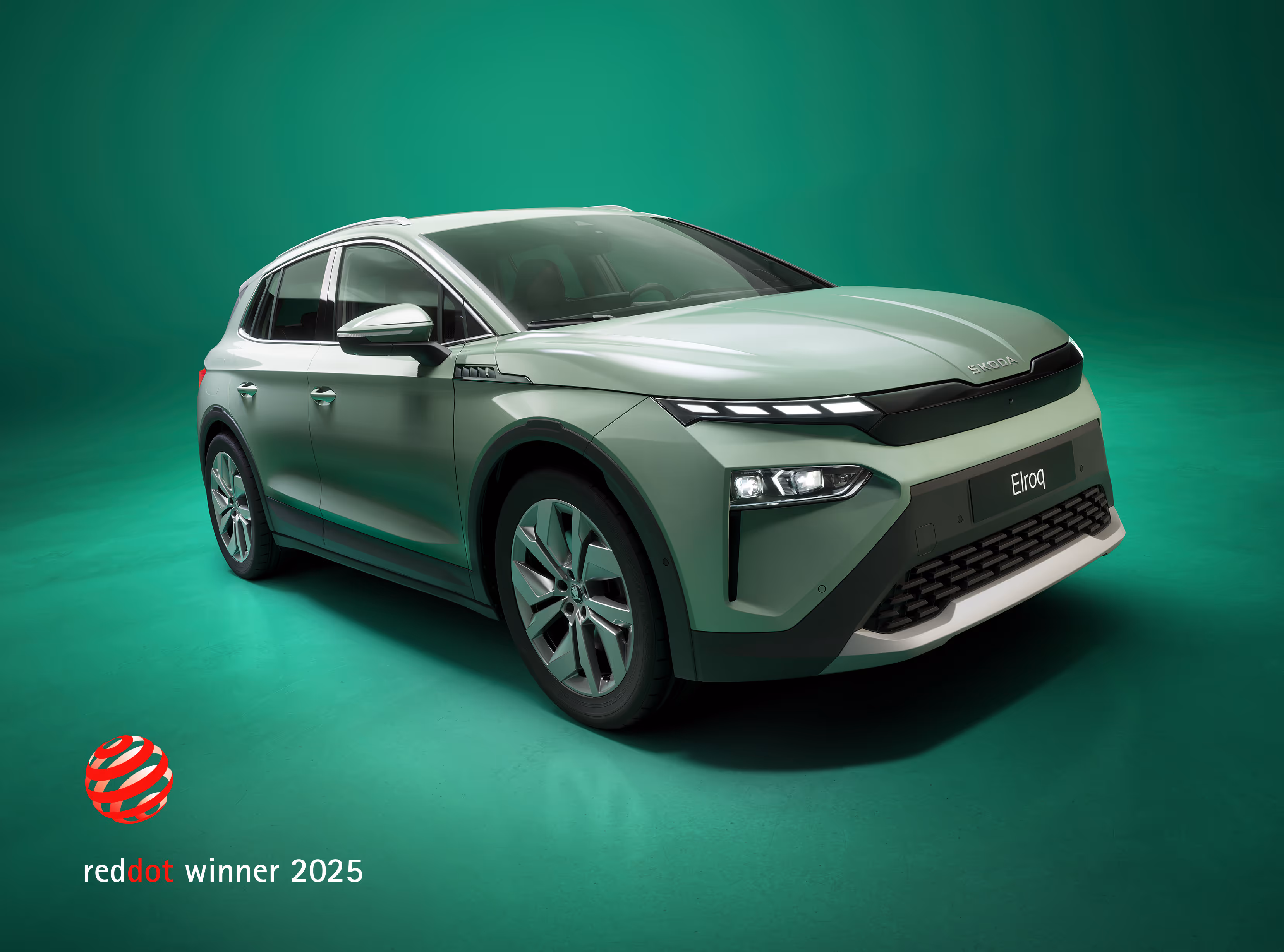 Schräge Frontalansicht eines Škoda Elroq in der Farbe Timiano-Grün vor einem grünem Studiohintergrund. In der unteren linken Ecke ist das "red dot winner 2025" Logo zu sehen, das eine Designauszeichnung darstellt.
